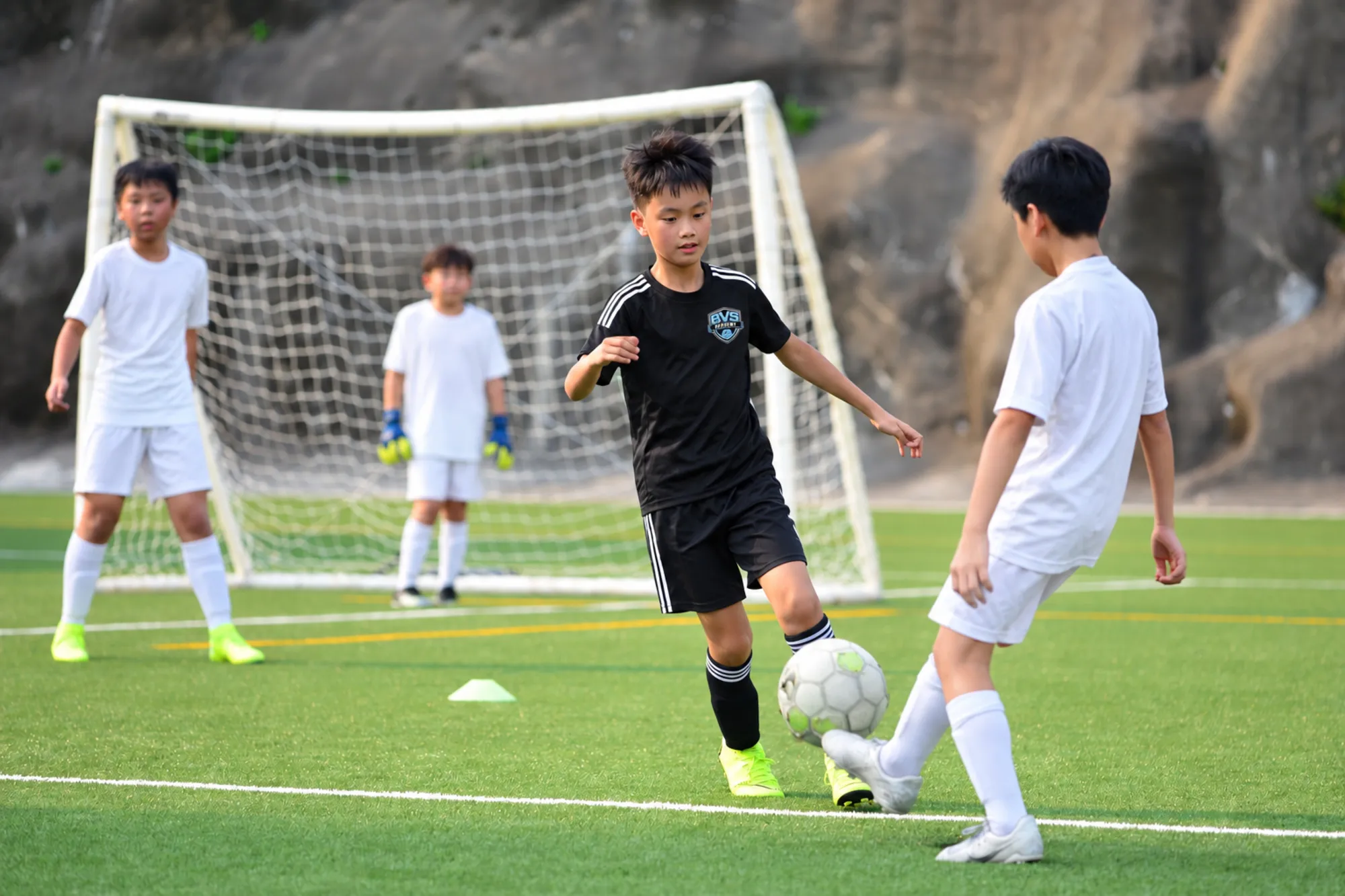 Young players competing for the ball on an artificial turf field