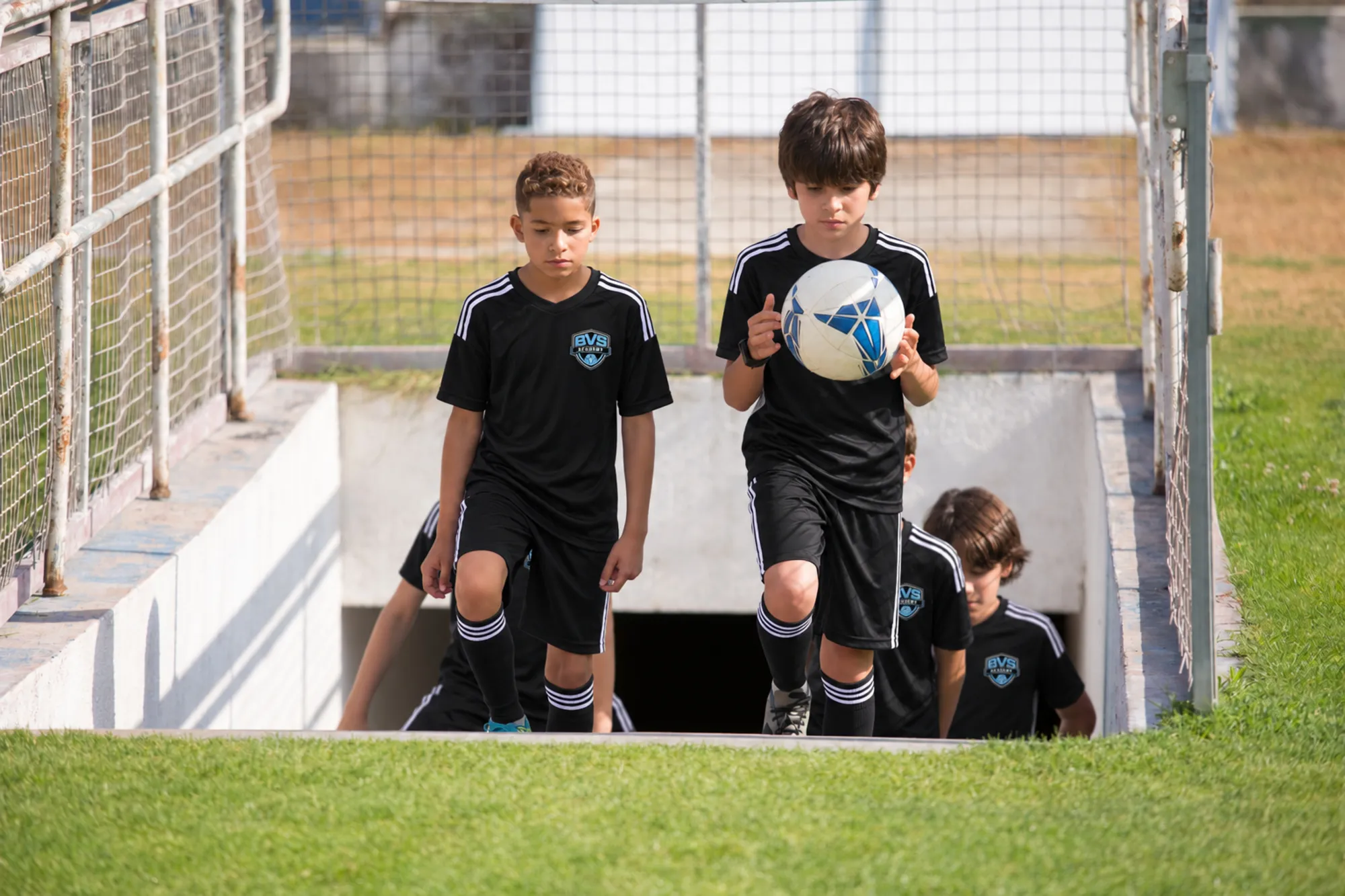 Young players walking out of the tunnel onto the stadium field
